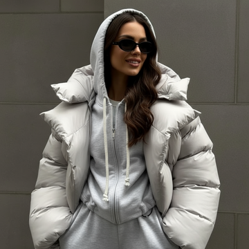 kobieta w czarnej pikowanej kurtce, białym topie i niebieskich spodniach dresowych